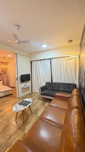 a living room with a leather couch and a tv at 7 Star homes at Rajhans Belliza in Surat