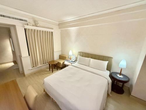 a hotel room with a large white bed and a desk at 種子商旅 in Kaohsiung