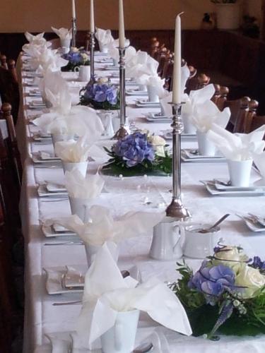 a long table with white plates and candles and flowers at Landhotel zur guten Quelle in Eisenach