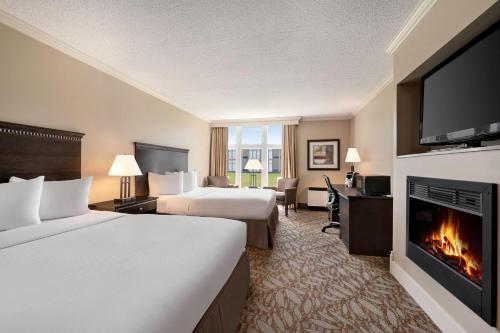 a hotel room with two beds and a fireplace at Ramada by Wyndham Cornwall in Cornwall