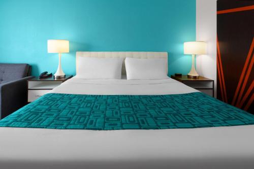 a bedroom with a white bed and two lamps at Howard Johnson by Wyndham Romulus Detroit Metro Airport in Romulus