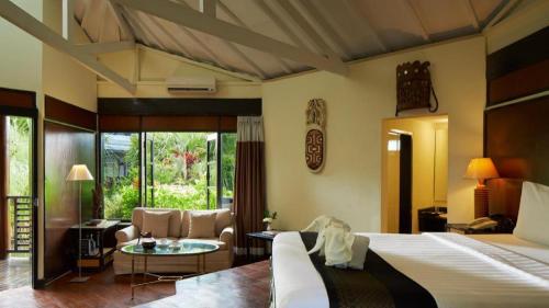 a bedroom with a bed and a living room at eL Hotel Kartika Wijaya Batu in Malang