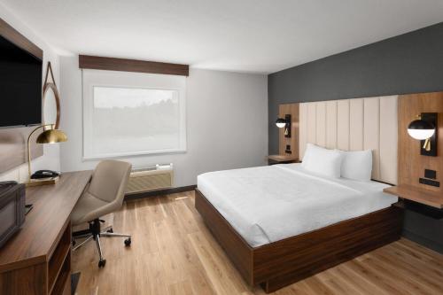 a hotel room with a bed and a desk and a computer at La Quinta by Wyndham Springdale in Springdale