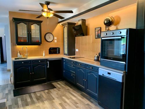 a kitchen with blue cabinets and a clock on the wall at Le 007 Refuge -Rurale gîte élégant piscine privée in Queyssac