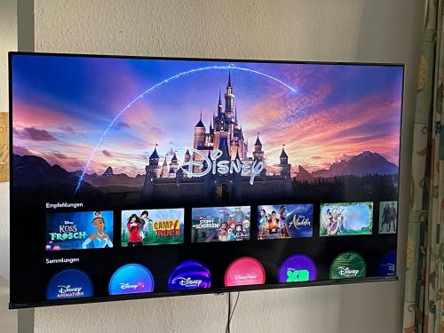 Un televisor de pantalla plana en una pared con un castillo de Disney. en Familienauszeit mit Indoorpool, Sauna, Netflix, Disney, 50-100 MBit Internet inkl Bettwäsche Handtücher Reinigung, en Missen-Wilhams