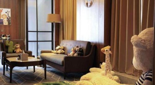 a living room with a couch and a chair with stuffed animals at Chongqing The Lotus Hotel in Chongqing