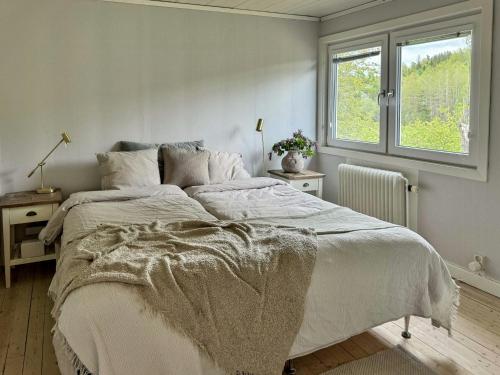 a white bedroom with a large bed and a window at Big House With A View Over Forest Lake in Hölö