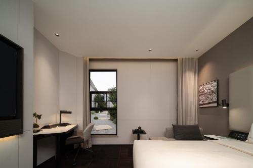 a bedroom with a bed and a desk and a window at Atour Hotel Shanghai The Bund Yuyuan Subway Station in Shanghai