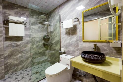 a bathroom with a toilet and a sink and a mirror at Wulingyuan Zhangjiajie National Forest Park Qique Villa in Zhangjiajie
