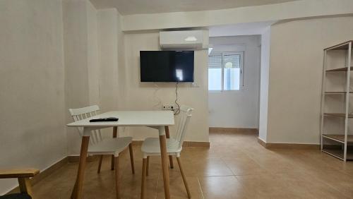 Un comedor con mesa y sillas y un televisor. en Apartamento para pareja en Jaén, en Jaén