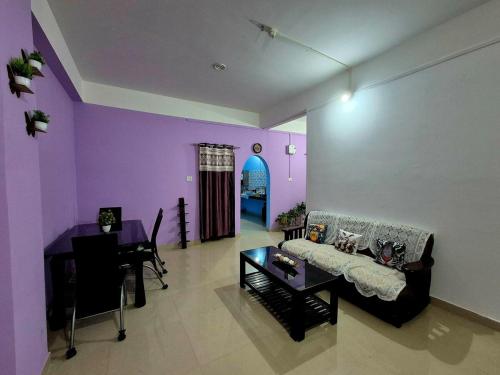 a living room with purple walls and a couch and a table at Aabir Home Stay in Guwahati