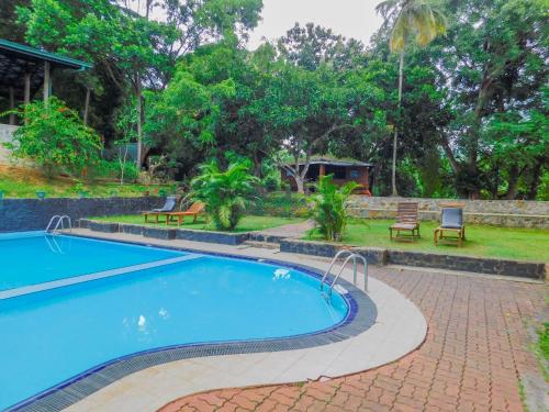 a swimming pool in a resort with benches and trees at Oruthota Chalets in Kandy