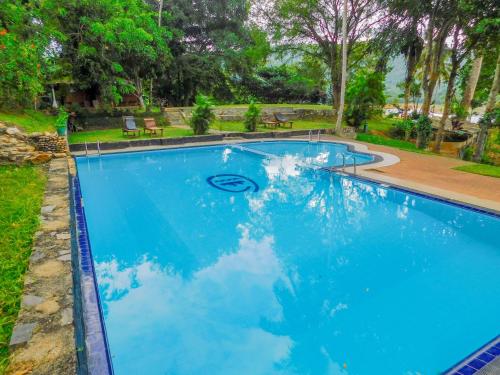 a swimming pool with blue water in a yard at Oruthota Chalets in Kandy