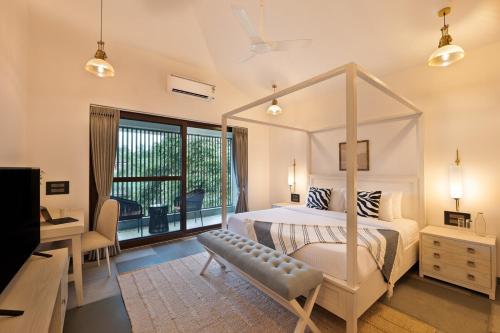 Un dormitorio con una cama con dosel y un escritorio. en Melhor stays villas - L-S10 4BHK villa with private pool, Anjuna, en Anjuna