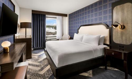 a hotel room with a bed and a television at The Brock Niagara Falls Fallsview, Tapestry by Hilton in Niagara Falls