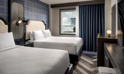 a hotel room with two beds and a window at The Brock Niagara Falls Fallsview, Tapestry by Hilton in Niagara Falls