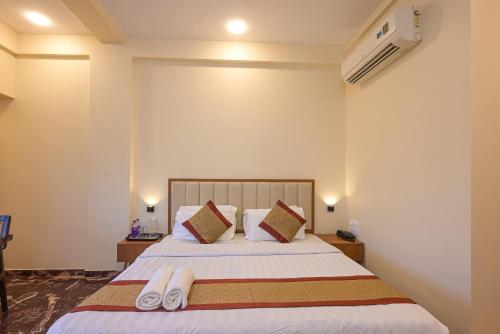 a bedroom with a bed with two slippers on it at Hotel Aristro Lonavala in Lonavala