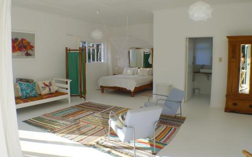 um quarto branco com uma cama e uma cadeira em Pashasha Beach House em Hermanus