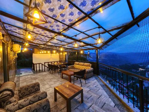 a patio with couches and tables on a balcony at Sirhind Regency - Budget Friendly !! Travellers Delight !! Luxury Rooms !! Best Awarded in Shimla