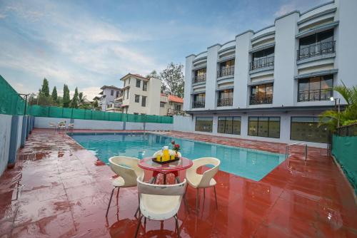 a pool with chairs and a table in front of a building at Hotel Aristro Lonavala in Lonavala