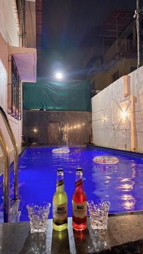 ロナバラにあるMaharaja Villaのプールの横のテーブルに置かれた2本の飲み物