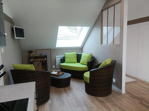 a living room with green chairs and a skylight at Les caves Sainte Anne in Écommoy