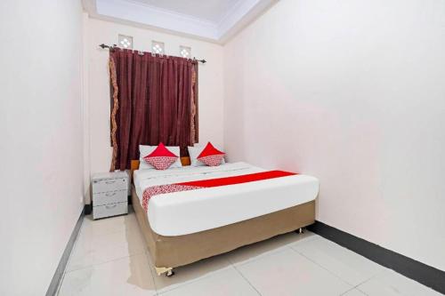 a bedroom with a bed with red pillows on it at Hotel O Jawara Guest House Syariah in Bandung