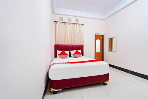 a bedroom with a bed with red and white sheets at Hotel O Jawara Guest House Syariah in Bandung