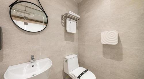 a bathroom with a toilet and a sink and a mirror at Crossing Hotel in Seoul