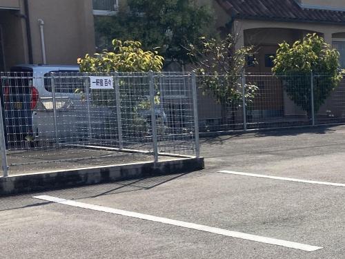 a fence in a parking lot next to a building at 一軒宿 百々 private house rental doudou in Mitoyo