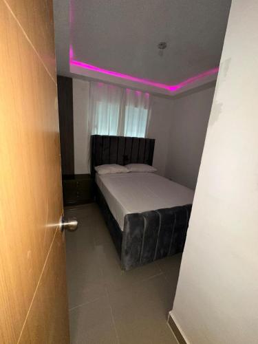 a small bedroom with a bed with a pink light at Bienvenido a tu refugio de lujo in Santo Domingo