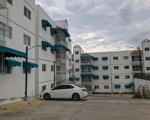 a white car parked in a parking lot in front of a building at Bienvenido a tu refugio de lujo in Santo Domingo