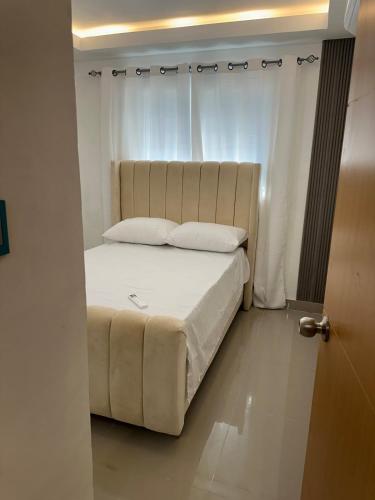 a bed with white sheets and pillows in a room at Bienvenido a tu refugio de lujo in Santo Domingo