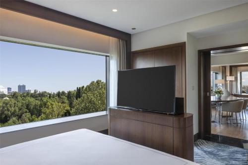 a bedroom with a flat screen tv and a large window at Conrad Istanbul Bosphorus in Istanbul