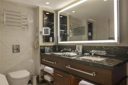 a bathroom with a sink and a toilet and a mirror at Conrad Istanbul Bosphorus in Istanbul
