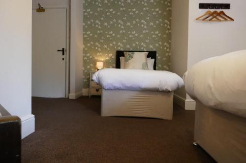 a bedroom with two beds and a wall with flowers at The Victoria in Malham