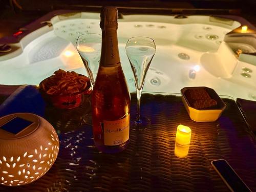 a bottle of wine and two wine glasses next to a hot tub at Chalet Chevreuil avec piscine privée in Lucéram