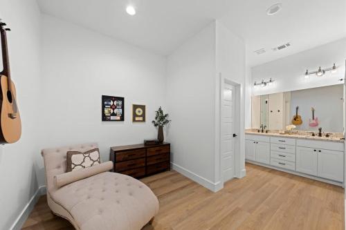 a white living room with a chair and a guitar at Hill Country Escape w/Views Plus, Hot-Tub and Pet Friendly! in Tivydale