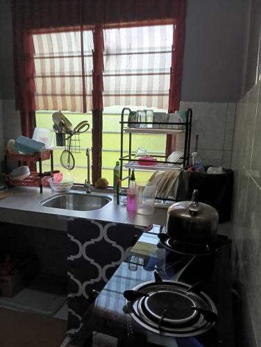 a kitchen with a sink and a stove and a window at Homestay MMr in Temerloh