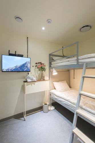 a bedroom with bunk beds and a flat screen tv at Nomad Hostel in Seoul