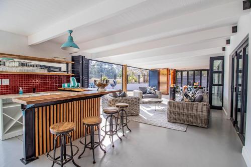 a kitchen and living room with a counter and stools at The Otters Oarsman Stanford Riverside Retreat in Stanford