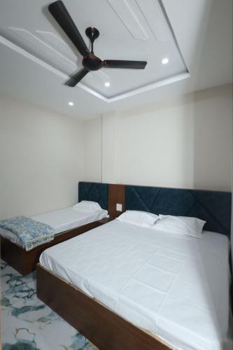 a bedroom with two beds and a ceiling fan at Hotel Shri Balaji Dham, Family Room Near Mathura Railway Station in Mathura