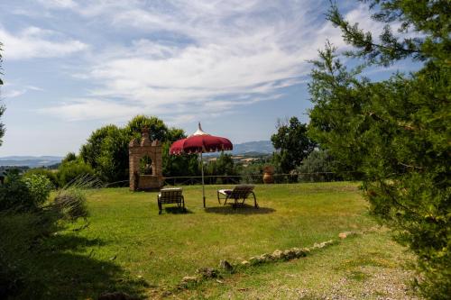 a table and two benches under a red umbrella at Podere del Botruccio in Pomarance