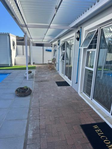 a patio with a white pergola next to a house at Pemba Guest Cape Town in Cape Town