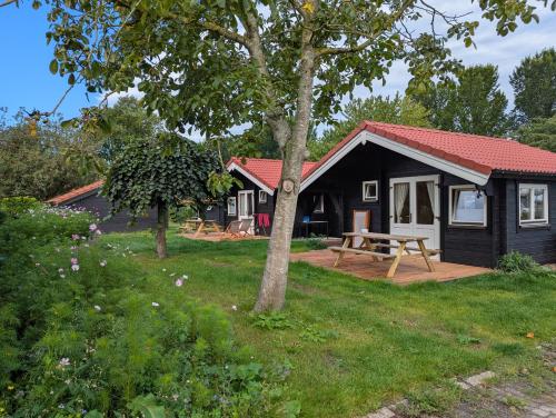 a black cottage with a picnic table in the yard at The Bee - Trekkershuts & Apartment in Opperdoes