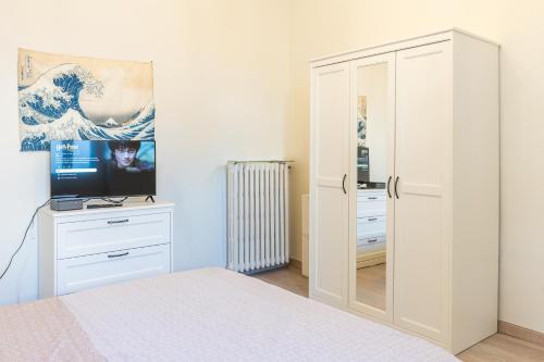 a bedroom with a bed and a desk with a television at Zen Retreat per Coppie con Jacuzzi - Dehor e Garage Privato - Check in Automatico 24 7 in Casale Monferrato