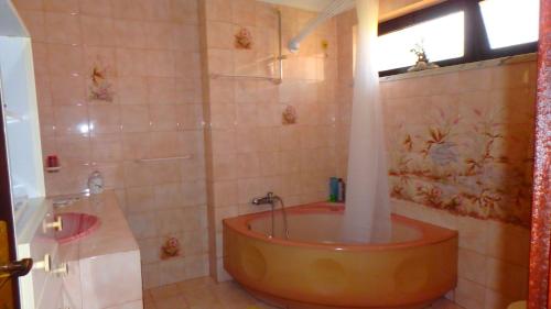 a bathroom with a tub and a shower with a window at Casa Teresinha in Sesimbra