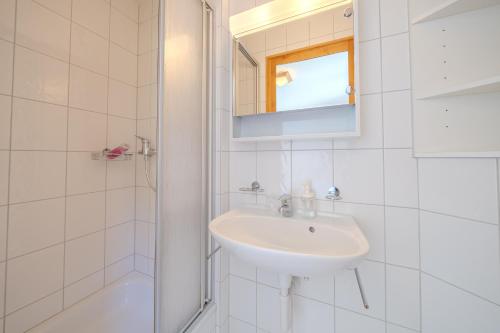 a white bathroom with a sink and a shower at Rothornblick 52 by Arosa Vacations, Wohnung mit Bergblick und Privatparkplatz in Arosa