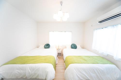 two beds in a room with white walls and a window at Miraie Kuwana Shimofukayabe 2 in Kuwana