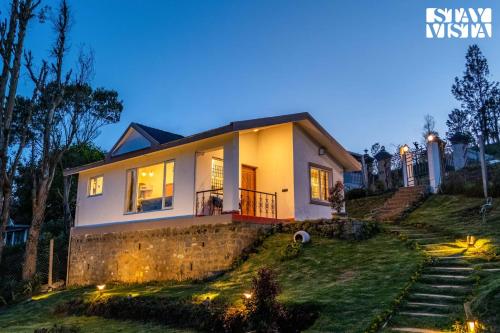 a house with lights on the side of it at StayVista at Rustling Pine with Bonfire, BBQ & Lawn in Ooty